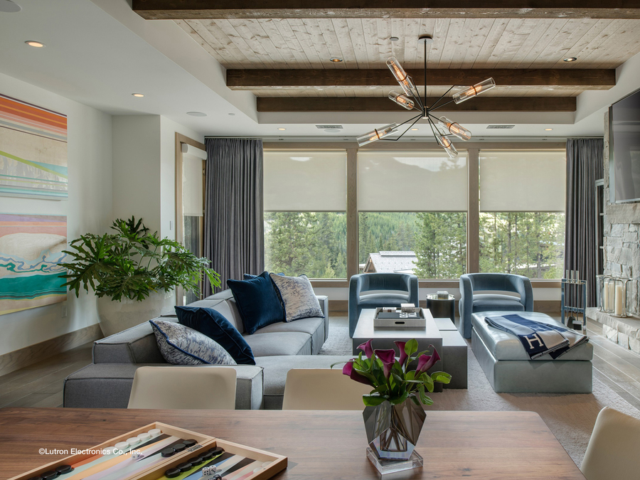 A living room with a large couch, two chairs, and large windows.